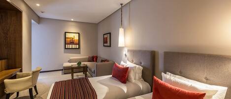 Una habitación de hotel con una cama, dos sillones, una mesita y un sofá.