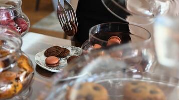 Una mesa con diversos postres, como galletas y macarons, en recipientes de vidrio transparente.