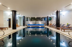 Una piscina techada, sillones reclinables de piscina