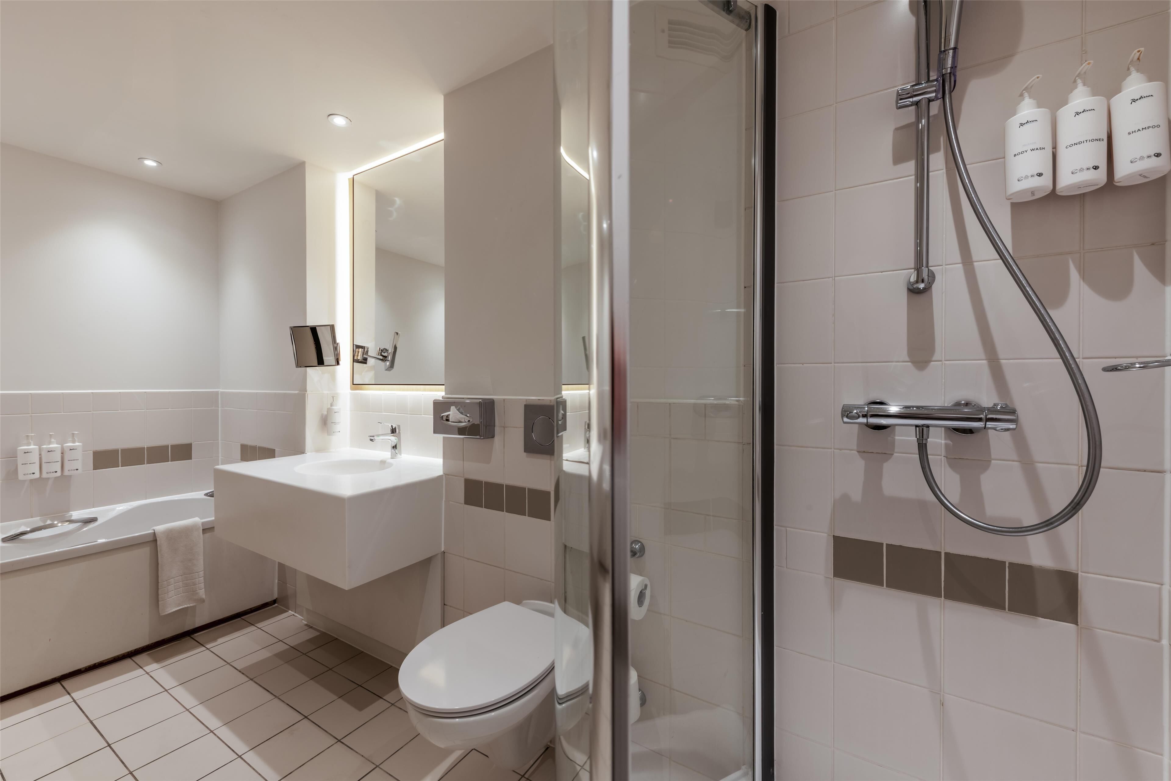A modern bathroom with a bathtub, toilet, and glass-enclosed shower area.