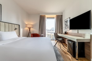 Relax in comfort with a large bed, desk, and flat-screen TV, offering a city view.