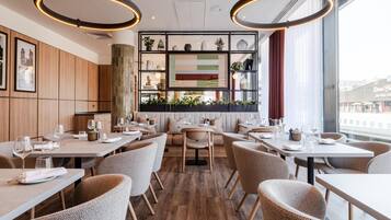 A modern restaurant interior with wooden panel walls, round tables, and chairs.