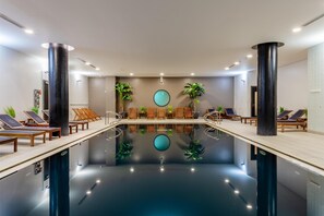 Relax by the serene pool surrounded by comfortable loungers and lush greenery.