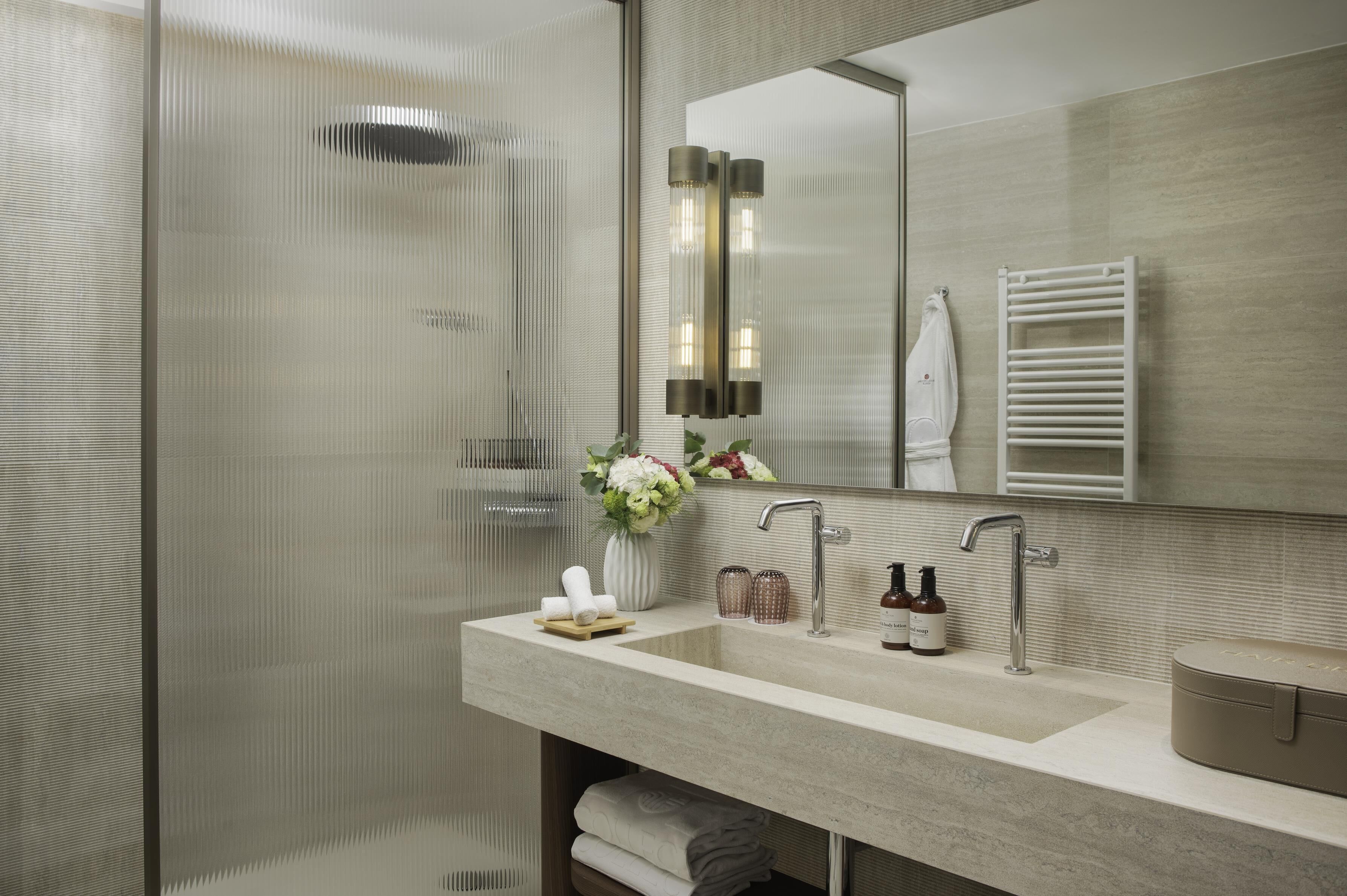 A modern bathroom with a glass shower enclosure, a vanity with a sink, and a towel rack.