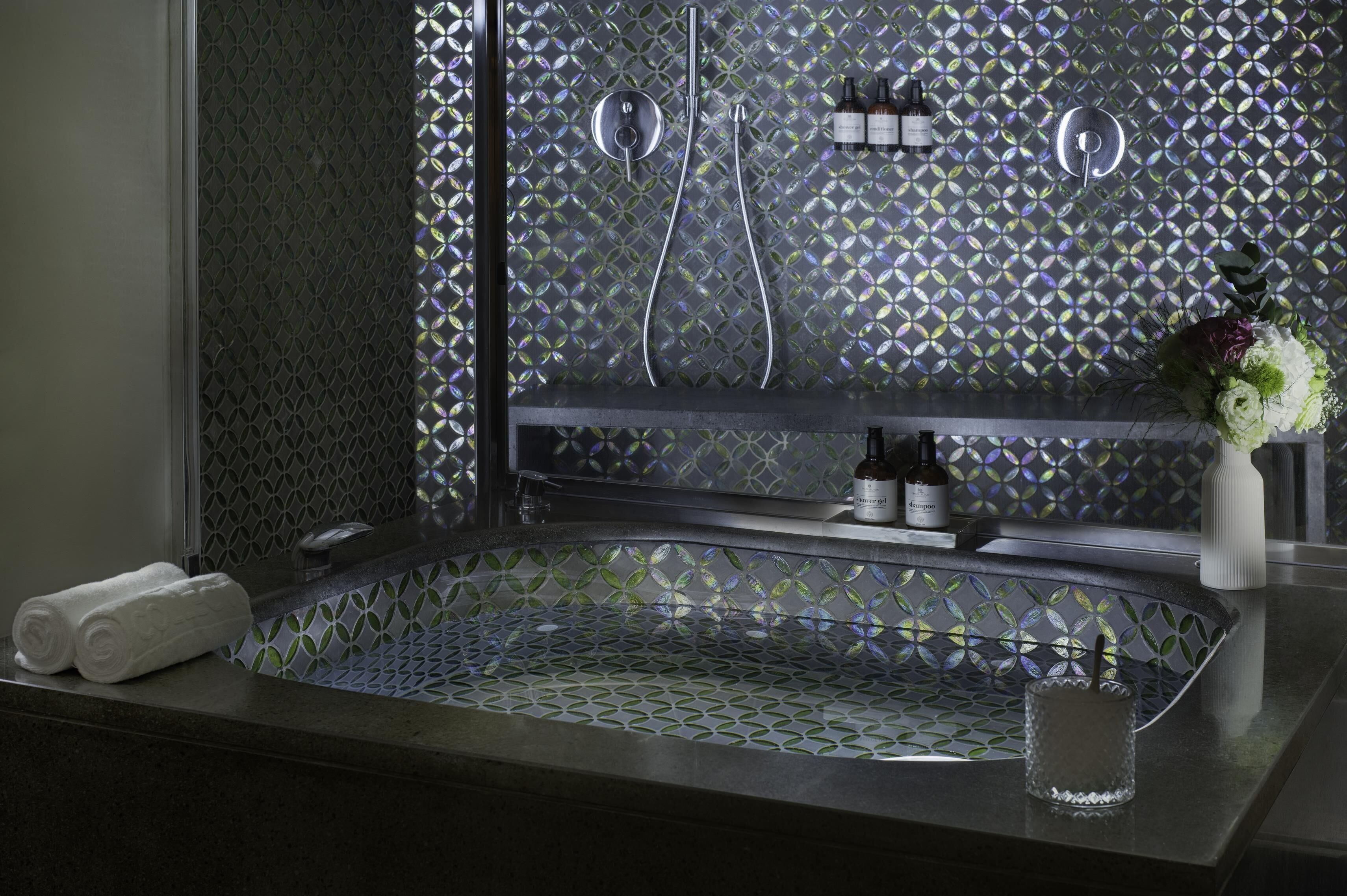 Un baño con una bañera independiente, ducha y tocador con artículos de aseo.