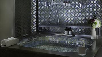 Un baño con una bañera independiente, ducha y tocador con artículos de aseo.