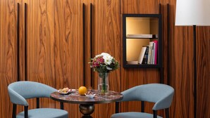 A room with two chairs, a table with a vase of flowers, and a bookshelf.