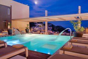Una piscina al aire libre, sillones reclinables de piscina