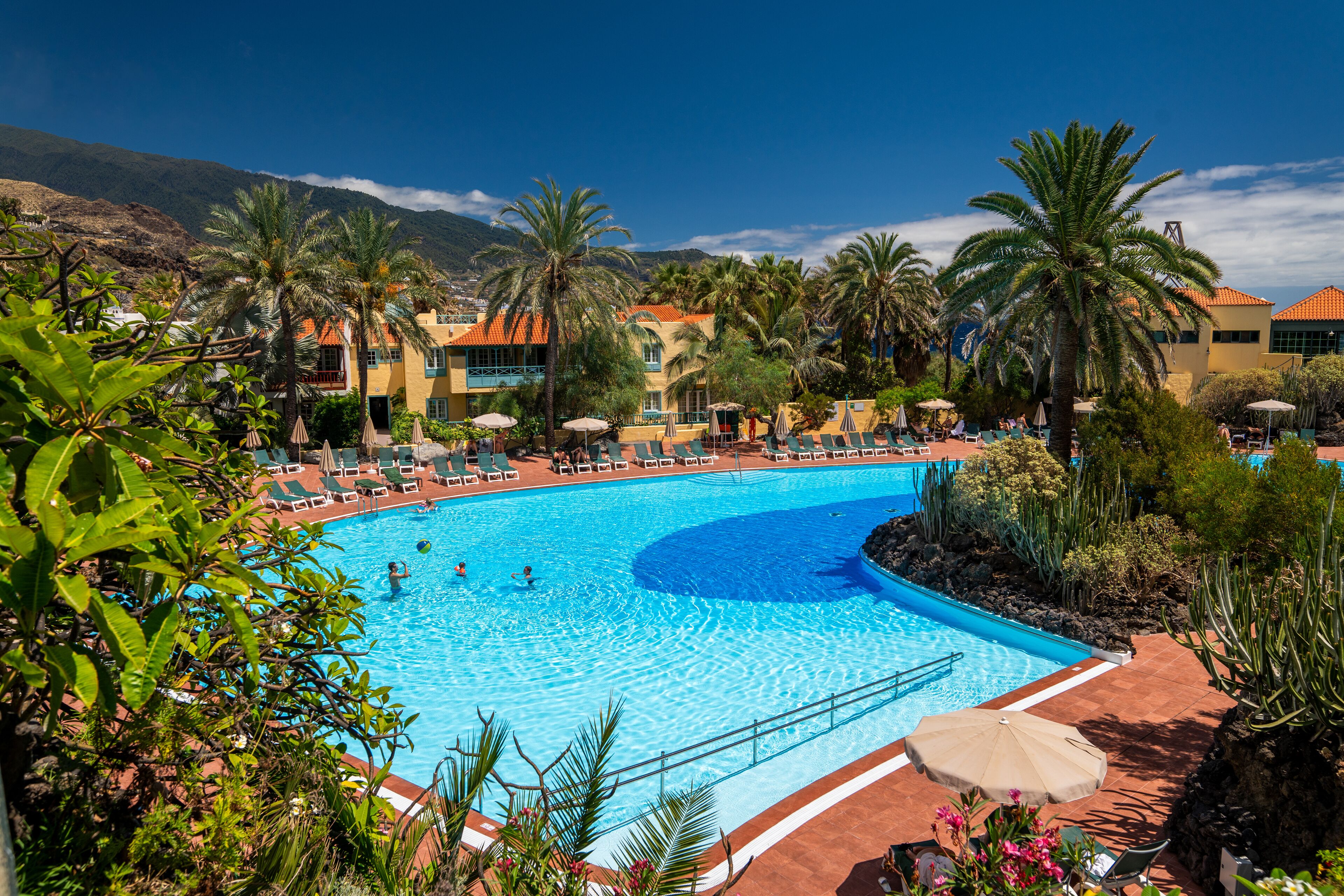 Una piscina al aire libre, sombrillas, tumbonas