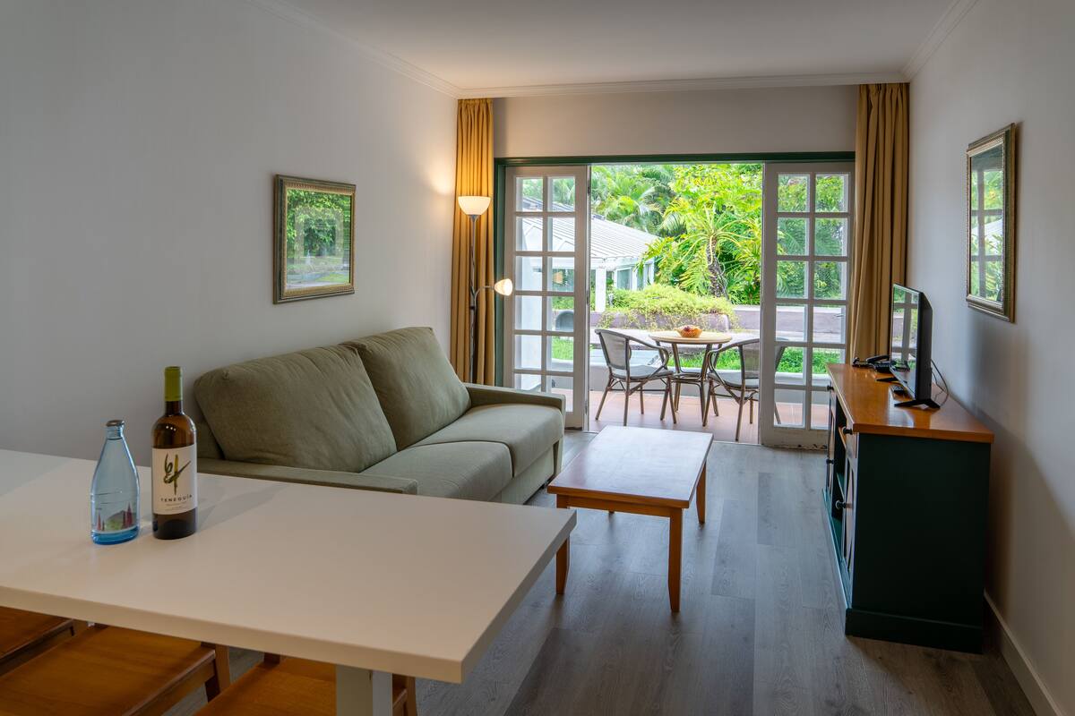 Ein modernes Wohnzimmer mit einer Couch, einem Esstisch und einer TV-Konsole.