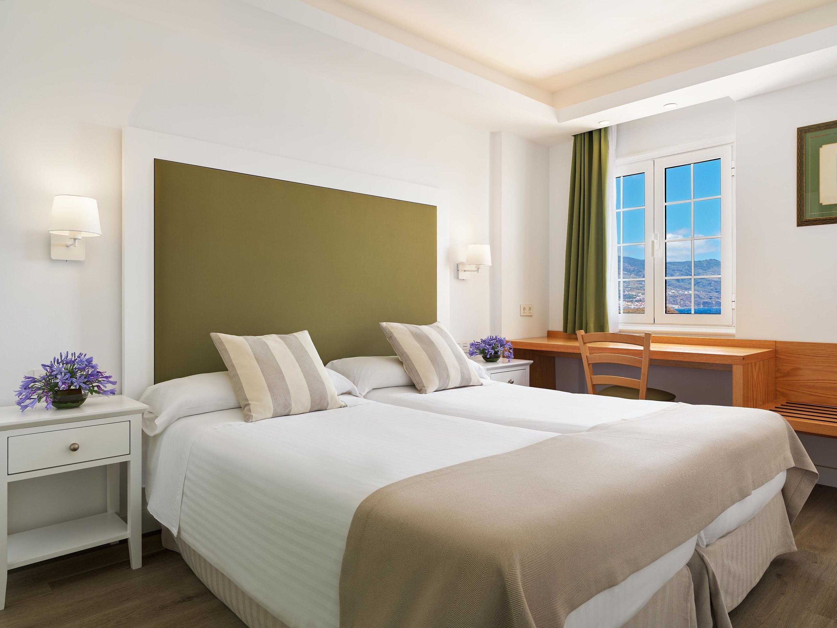 Una habitación de hotel con dos camas, un escritorio y una ventana con vistas.