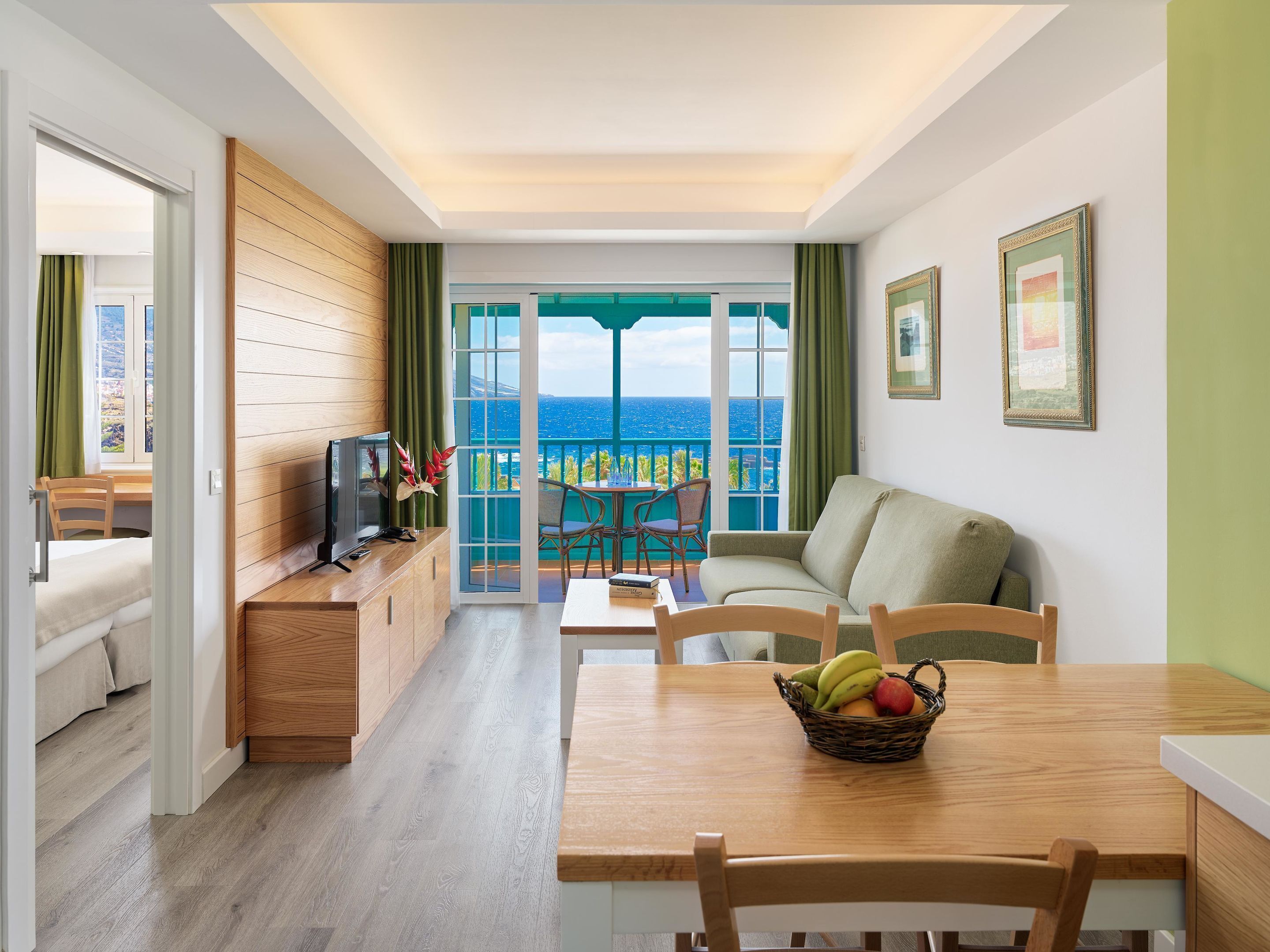 Une chambre d’hôtel moderne dotée d  ’un balcon, de meubles en bois, d’un coin repas et d’une télévision.
