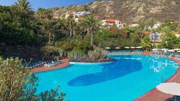 Una piscina al aire libre, sombrillas, tumbonas