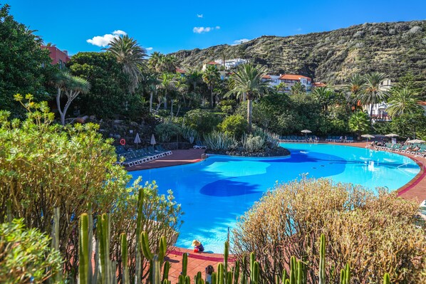 Una piscina al aire libre, sombrillas, sillones reclinables de piscina