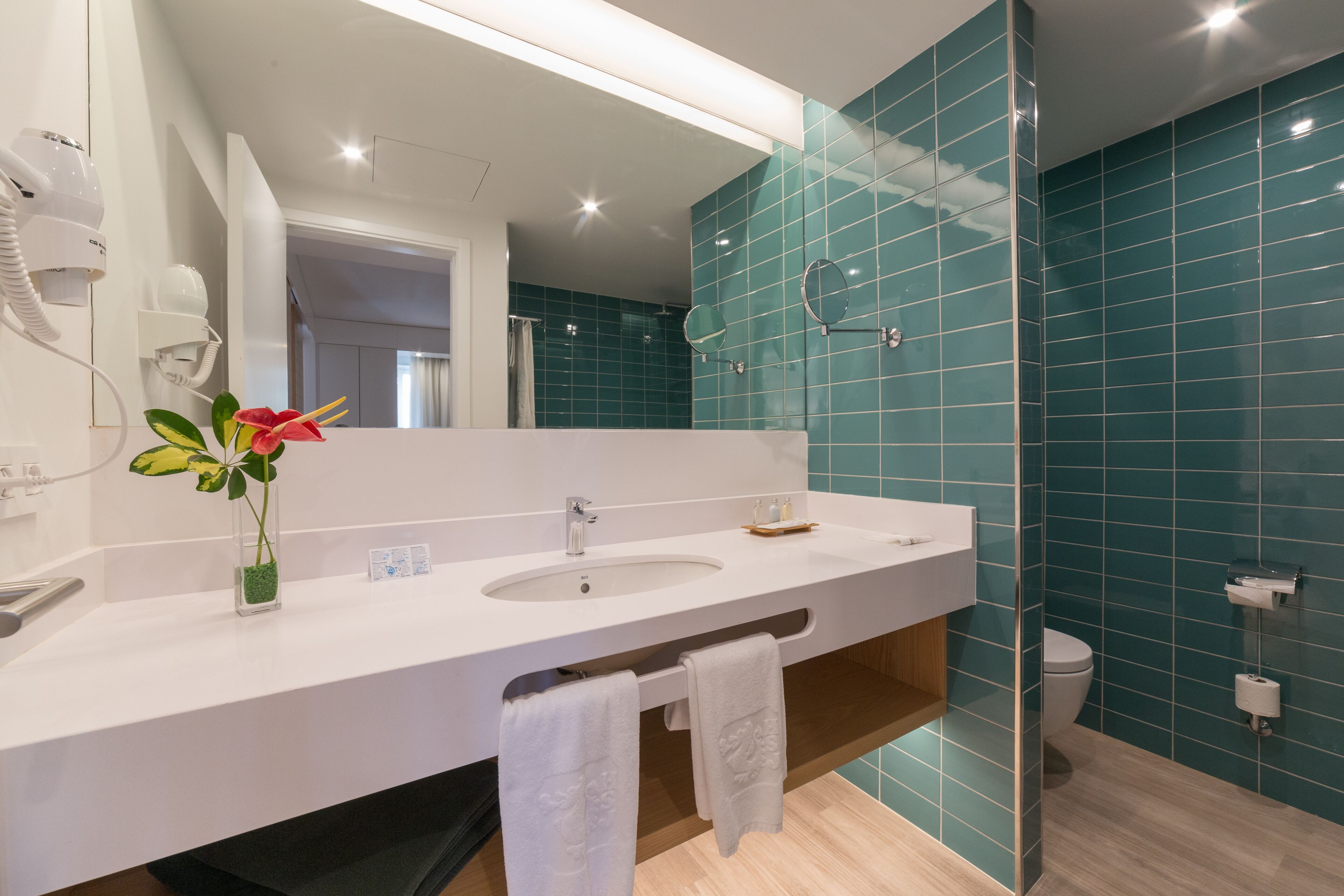 A modern bathroom with a white sink, a mirror, and a glass shower enclosure.