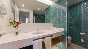A modern bathroom with a white sink, a mirror, and a glass shower enclosure.