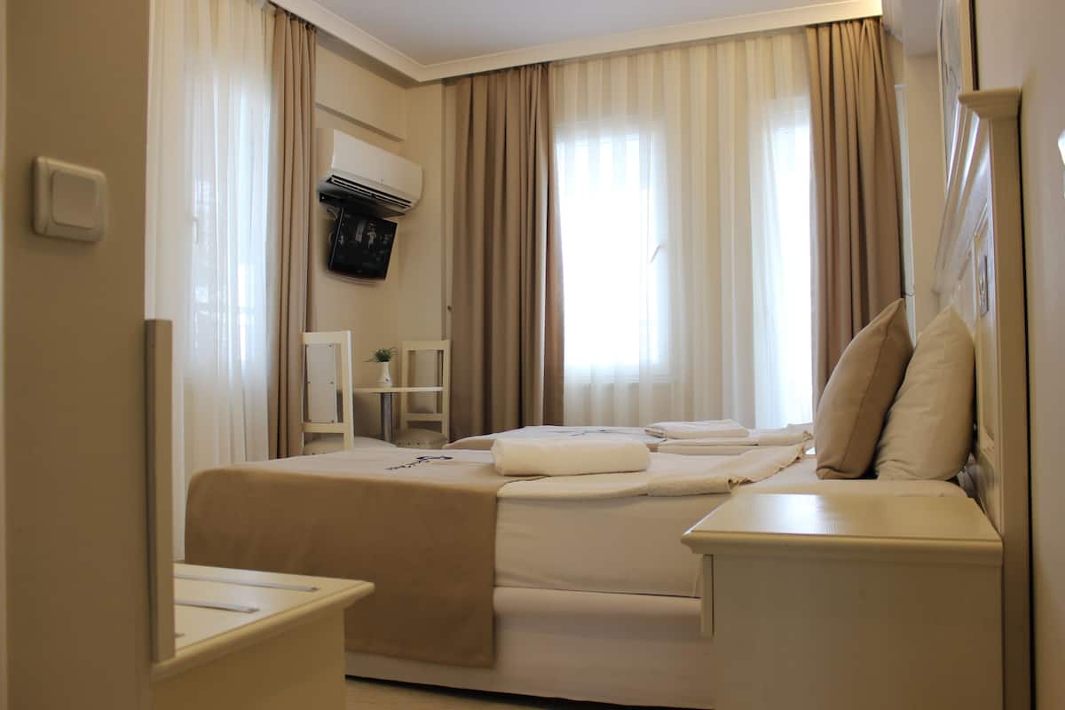 A hotel room with a bed, bedside tables, a chair, and a small table with a plant.
