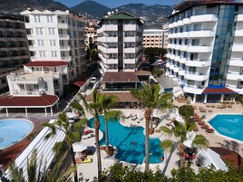 Ein Resort mit mehreren Schwimmbecken, Palmen und einer Bergkulisse.