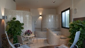 Un'area benessere con angolo relax, un tavolino con fiori e una pianta grande.
