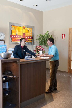 A reception desk with a clock, a large abstract painting, and a plant. - Luz del Mar (Los Silos)