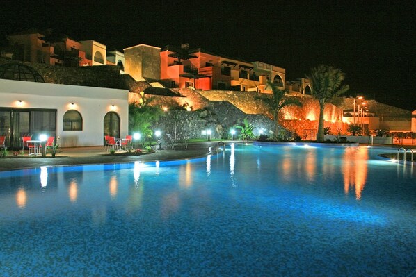 Una piscina al aire libre, sombrillas, tumbonas