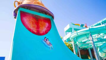 A water slide with a large fish design and a person sitting on the slide.