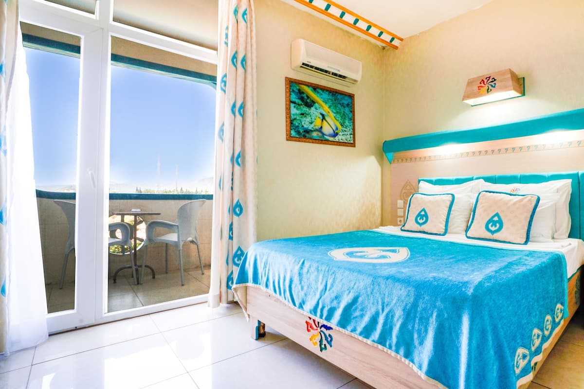 A hotel room with a bed, a nightstand, a phone, and a window with a view.