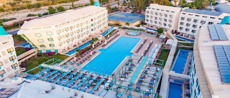 Un gran hotel con varias piscinas, cancha de tenis y diversas zonas de estar al aire libre.
