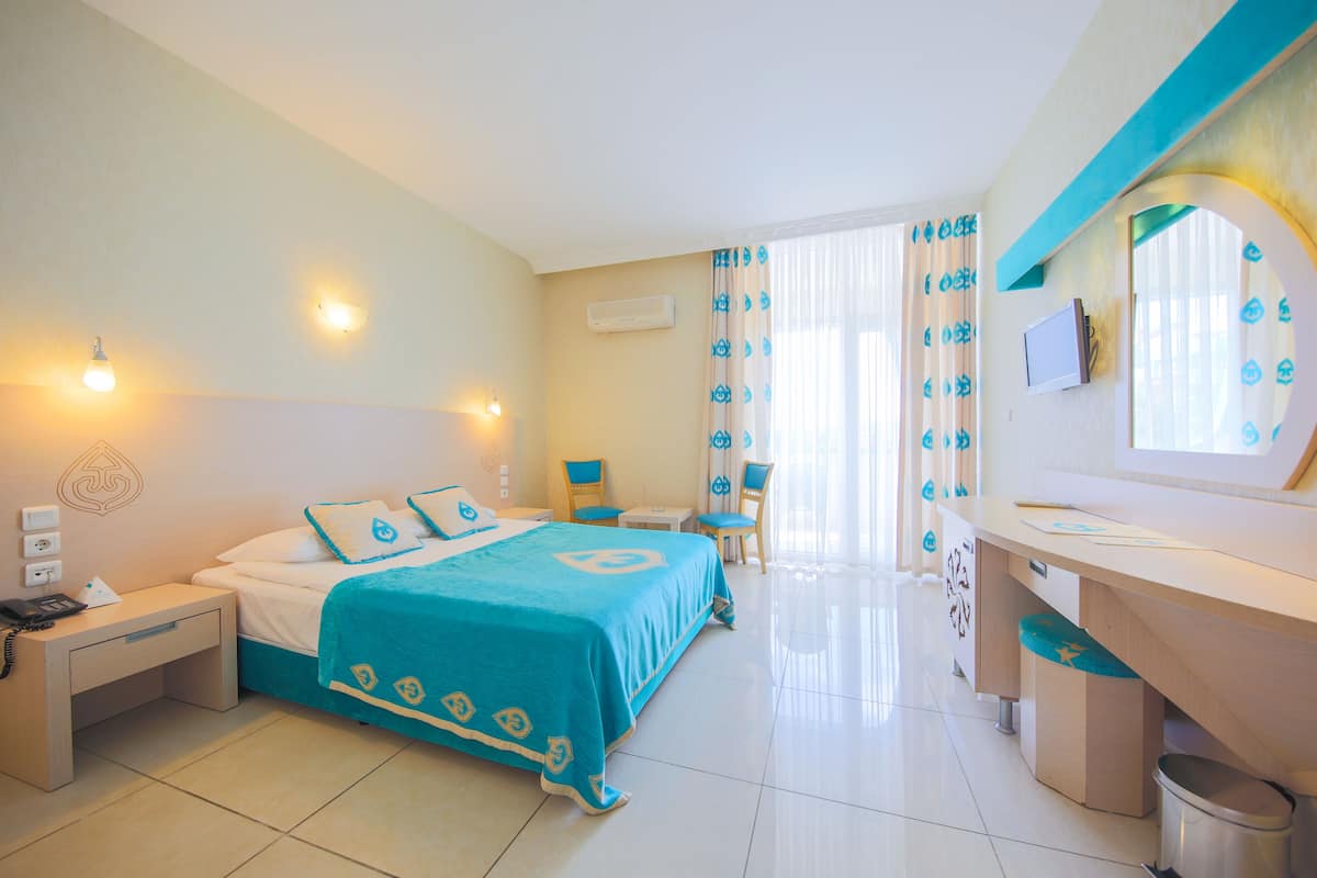 A hotel room with a bed, bedside tables, a desk, a chair, and a bathroom.
