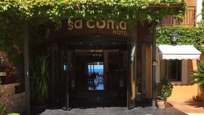 Ingången till Sacoma Hotel, med utsikt över havet genom glasdörrarna.