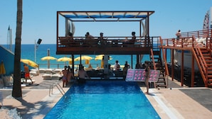 A swimming pool with a wooden deck, umbrellas, and a view of the sea. - Sealine Hotel (Alanya)