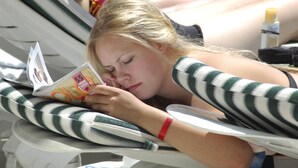 A person lying on a striped lounge chair by a pool, reading a magazine. - Sealine Hotel (Alanya)