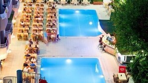 A rooftop pool area with multiple swimming pools, lounge chairs, and a water slide. - Sealine Hotel (Alanya)