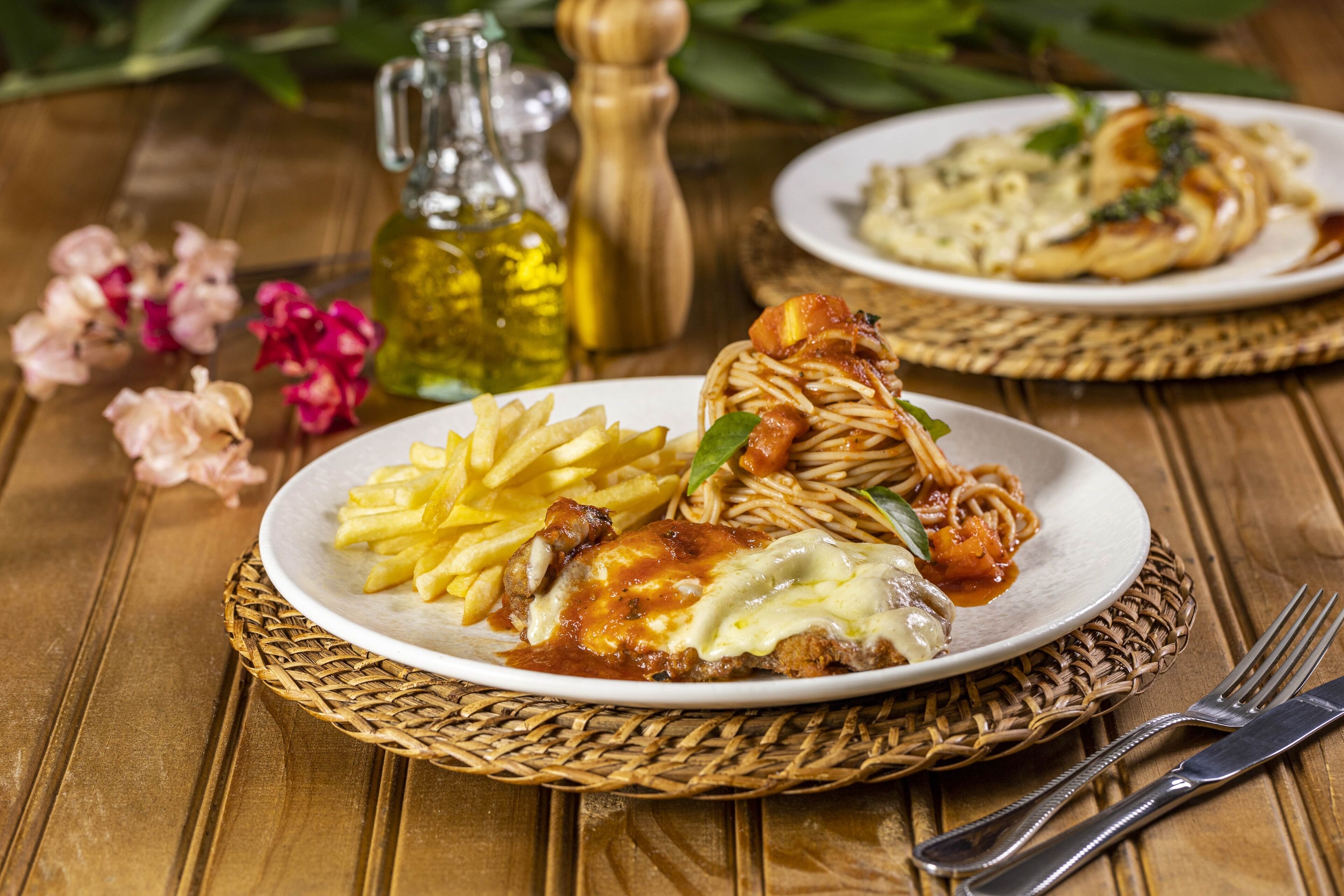 A plate of spaghetti with meatballs and a side of fries on a wooden table.
