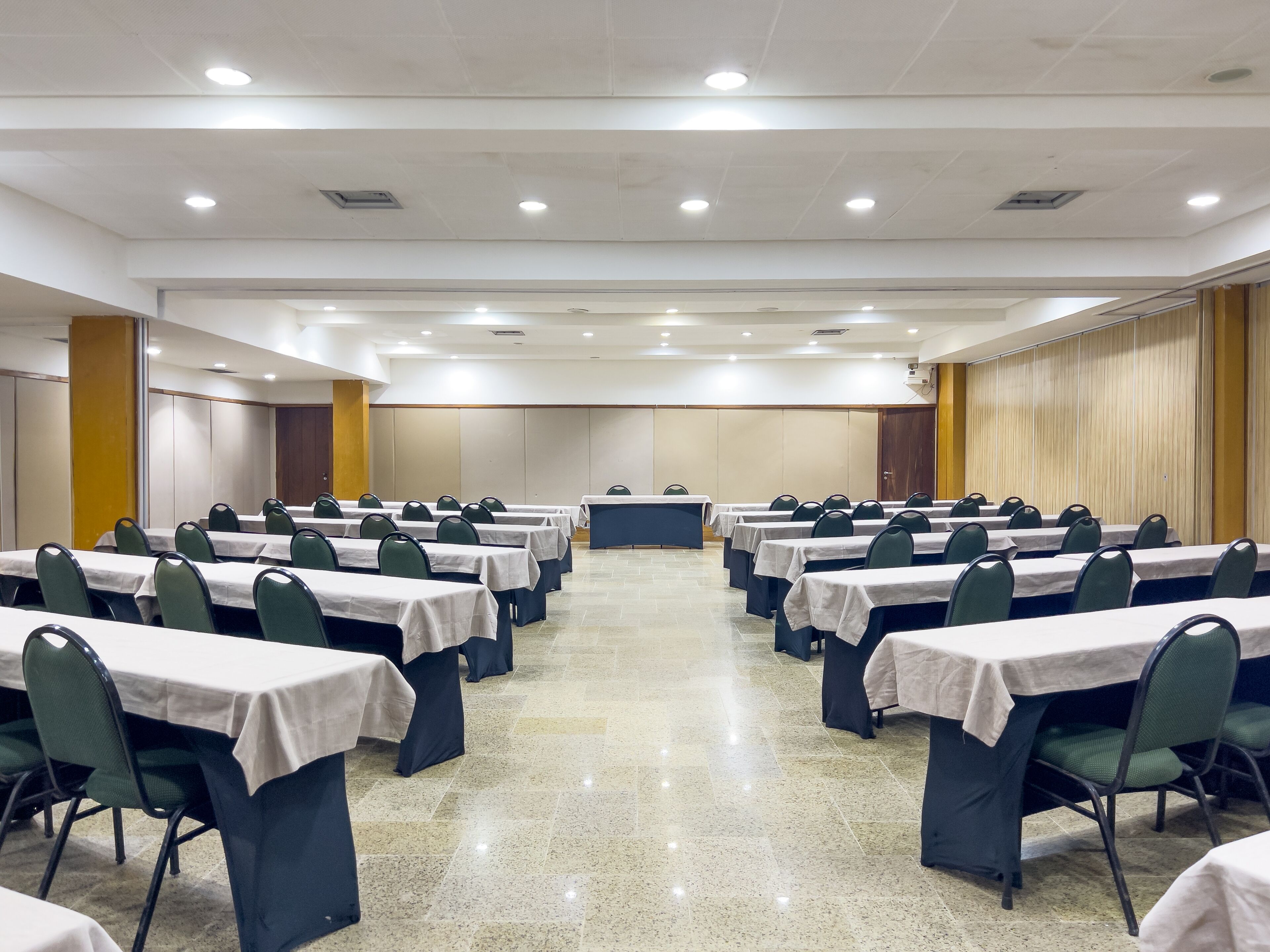 Une salle de conférence dotée de plusieurs tables et de nombreuses chaises, disposées en rangées.