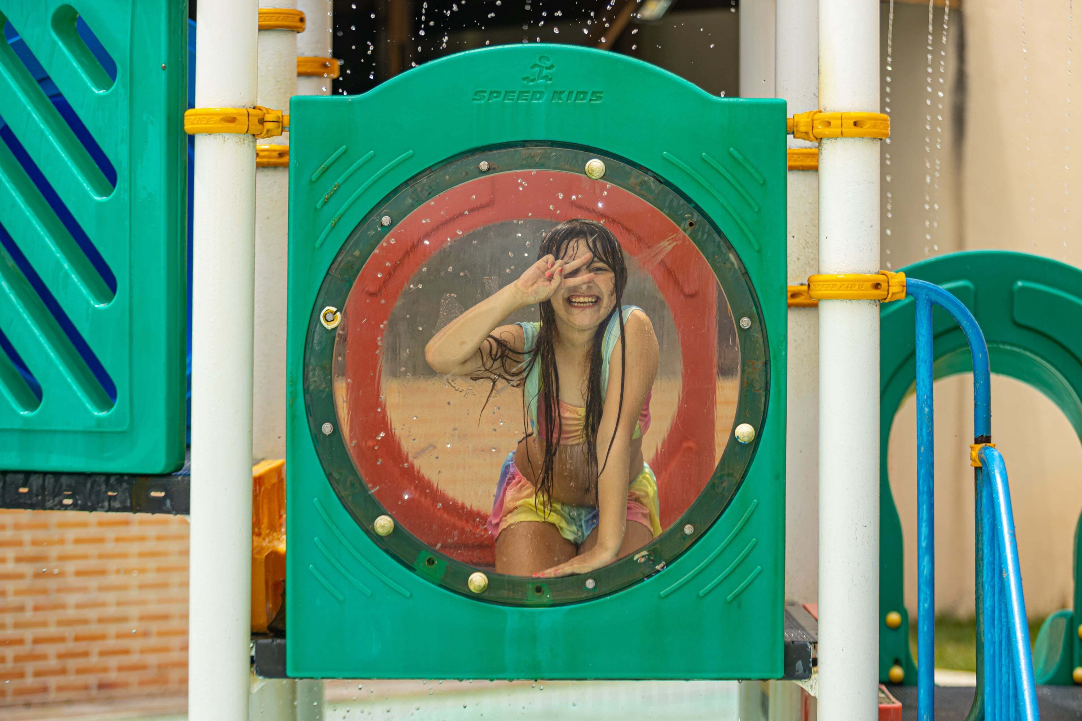 Zona de juegos acuáticos con un tobogán circular y una estructura verde.