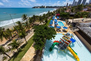 Un resort con área de piscina, tobogán de agua y playa.