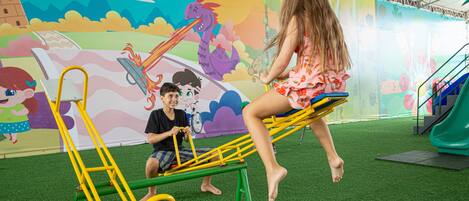 A child and an adult on a seesaw with a colorful mural in the background.