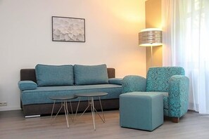 A modern living room with a sofa, ottoman, and two small tables. - Schlossberghotel (Greiz)