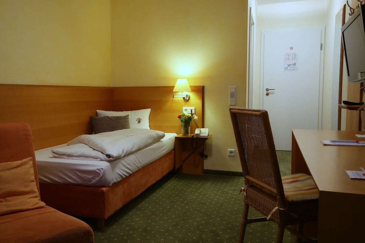 Una habitación de hotel con una cama, un escritorio, una silla y un sofá.