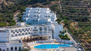 Un hôtel blanc à plusieurs étages, doté d’une piscine et offrant une vue sur le paysage environnant.