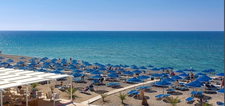 Sulla spiaggia, sabbia scura, lettini da mare, ombrelloni. Mare Village