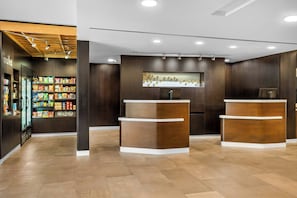 A reception area with a counter, a refrigerated display case, and a wall-mounted information board. - Courtyard by Marriott St Augustine I-95 (St. Augustine)