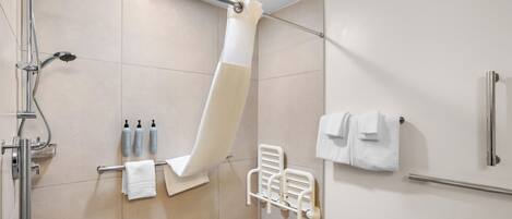 A modern bathroom with a shower, a towel rack, and a hand dryer.