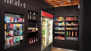 Interior de una tienda con estantes llenos de diversos productos, un expositor refrigerado y un letrero que dice 'market'.