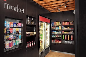 A store interior with shelves stocked with various products, a refrigerated display, and a 'market' sign on the wall.