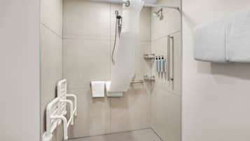 A modern bathroom with a shower, a towel rack, and a handrail.