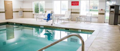 An indoor swimming pool with a clear view of the pool area, a door, and a sign indicating emergency procedures.
