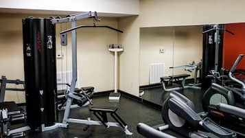 A gym with various exercise equipment, including a Smith machine, a bench, and a treadmill.