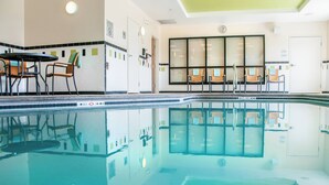 A swimming pool with chairs and tables around it, a clock on the wall, and a door. - Fairfield Inn & Suites Colorado Springs N./Air Force Academy (Colorado Springs)